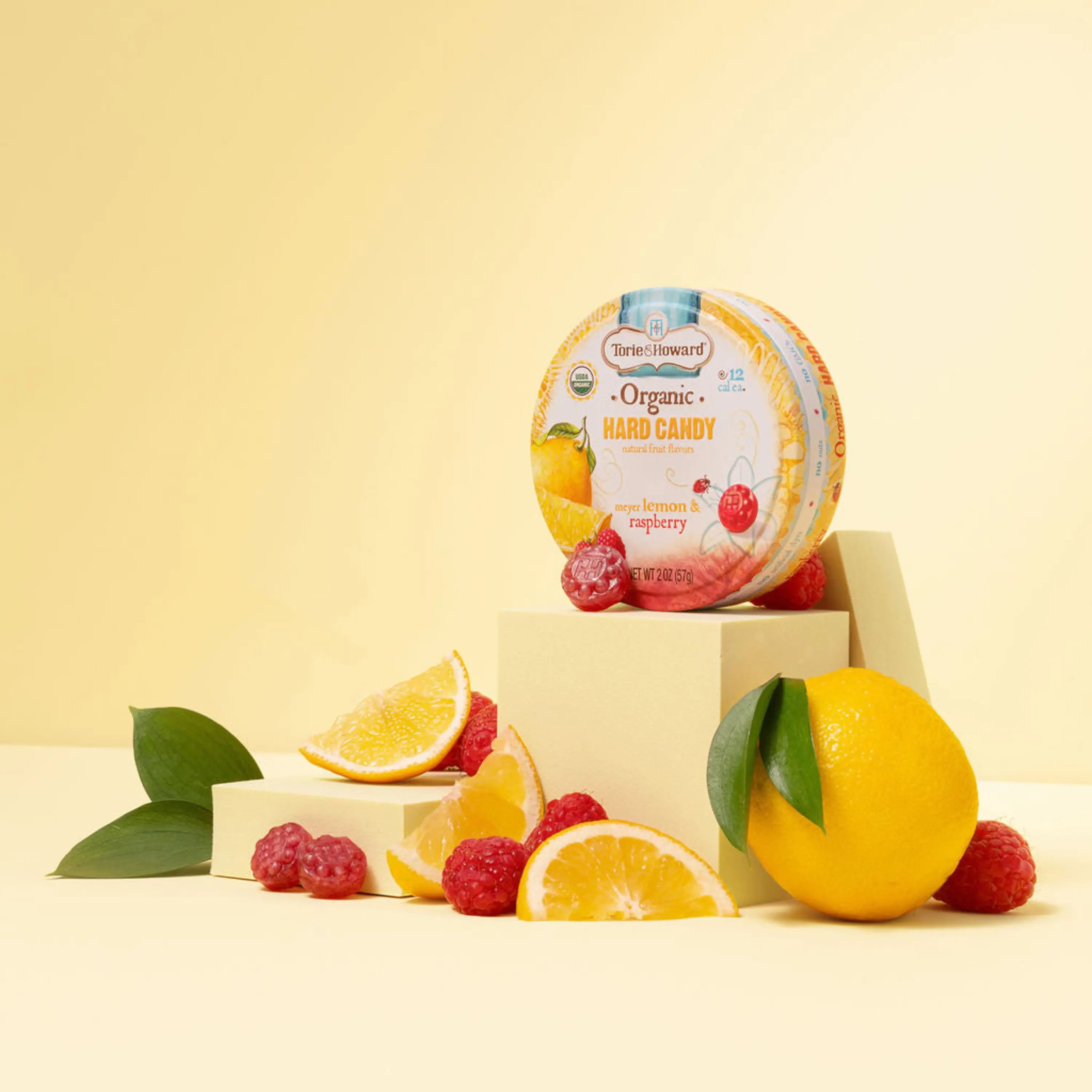 Torie & Howard Meyer Lemon & Raspberry Organic Hard Candy 2oz Tin with candies and fruits in front