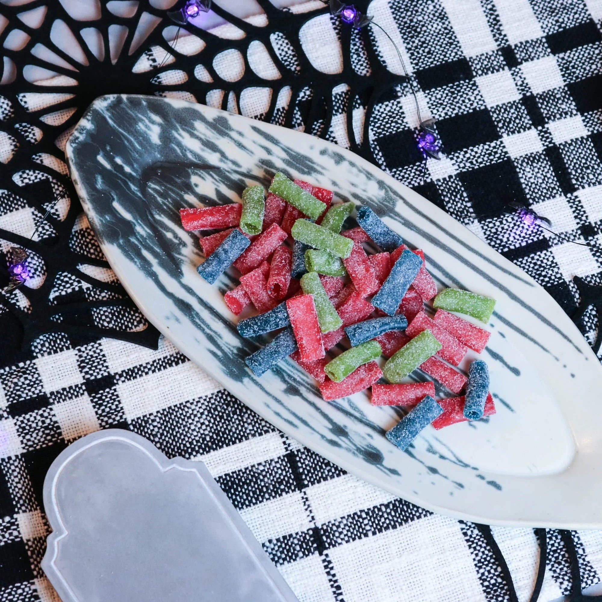 Sour Punch Assorted Bites Candy on a platter with a fake spiderweb and tombstone