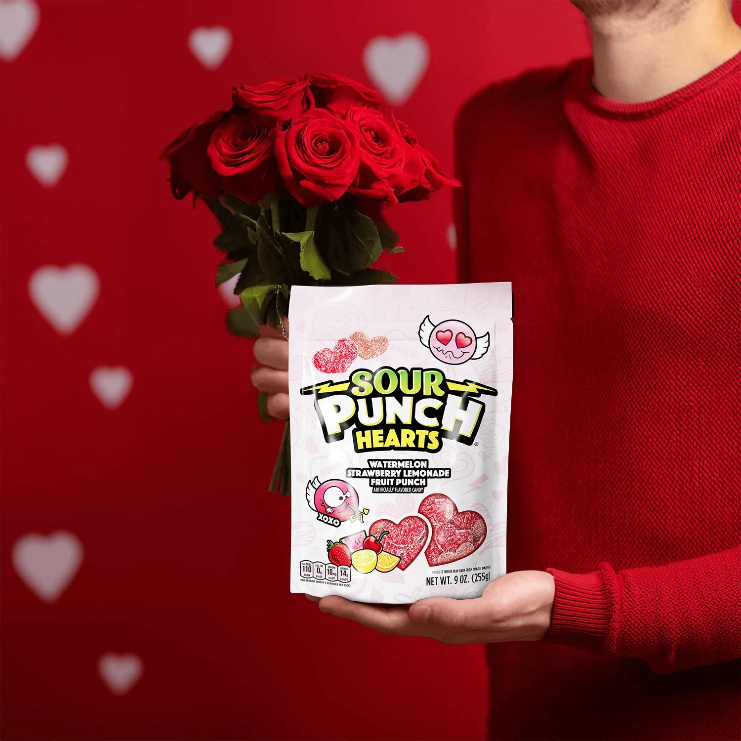 Person holding a Sour Punch Hearts Valentine's Day Candy 9oz Bag and red roses