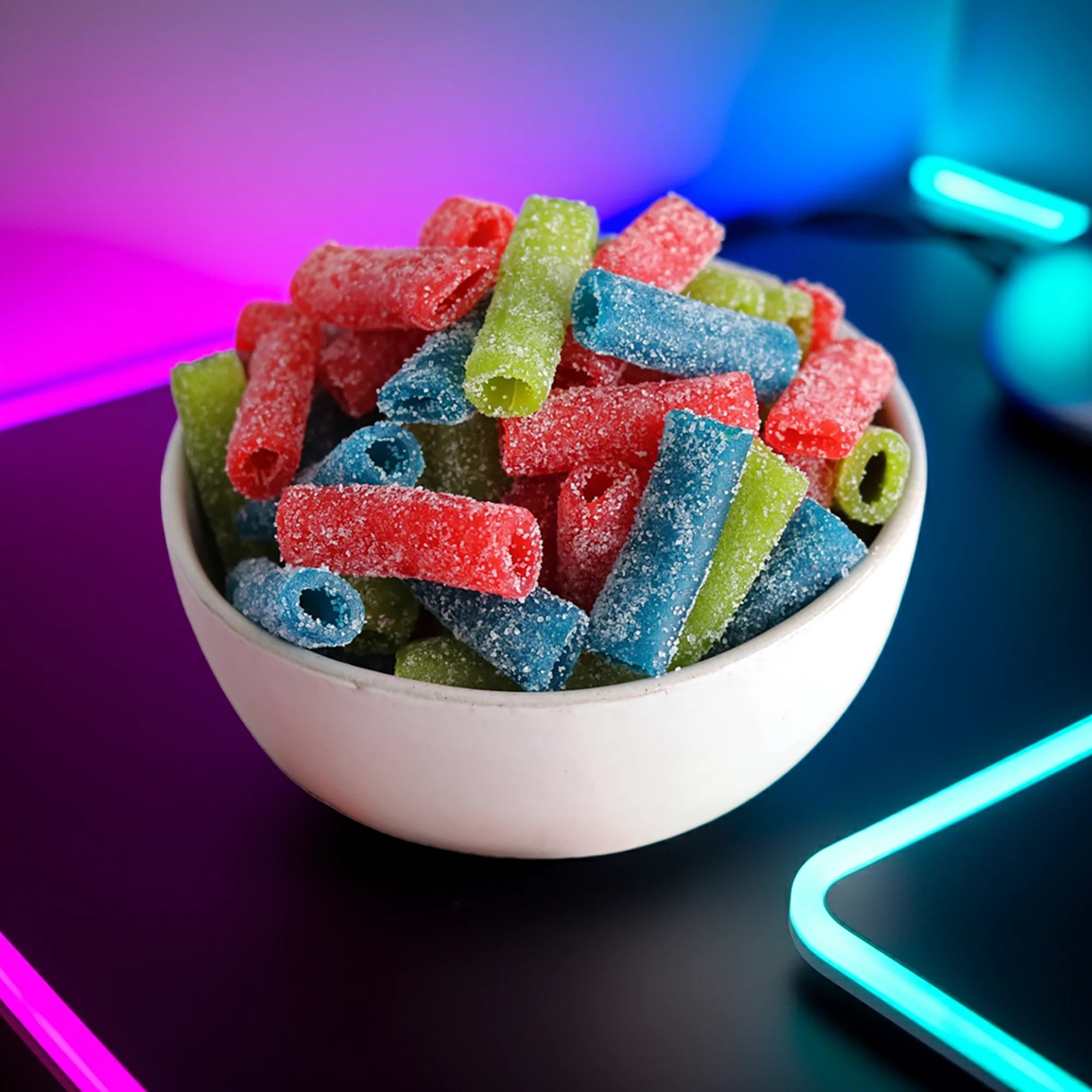 Bowl of assorted sour candy bites on a desk with neon lights
