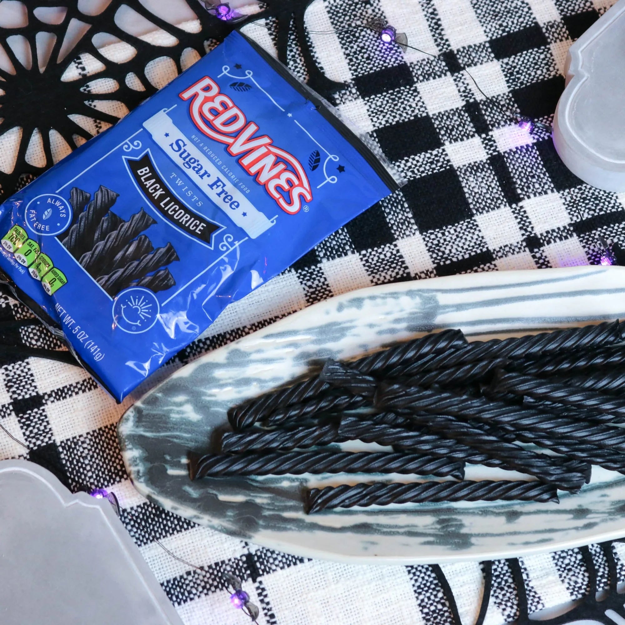 Red Vines Sugar Free Black Licorice Twists on a platter with a fake spiderweb and tombstone