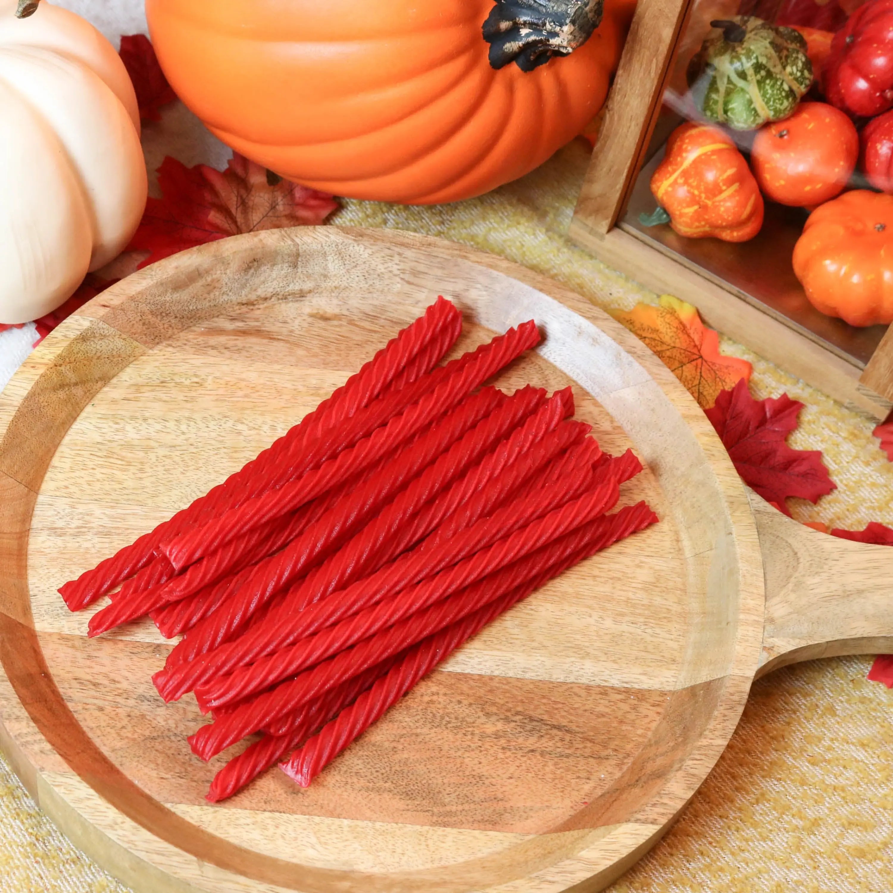 Red Vines Original Red Licorice Candy on a wooden platter surrounded by pumpkins and leaves