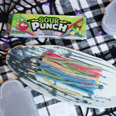 Sour Punch Rainbow Straws Candy on a platter with a fake spiderweb and tombstone