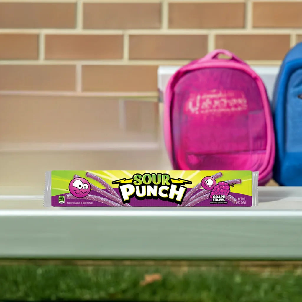 Sour Punch Grape Candy Straws 2oz Tray on a school bench with two backpacks in the background 