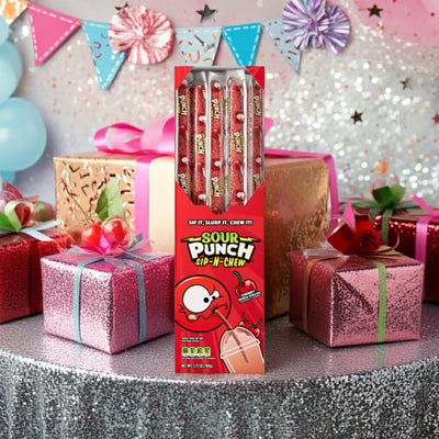 Caddy of Sour Punch Cherry Sip-N-Chew Straws on a table surrounded by birthday gifts and decorations