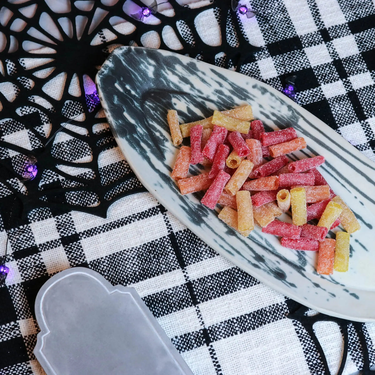 Sour Punch Tropical Bites Candy on a platter with a fake spiderweb and tombstone