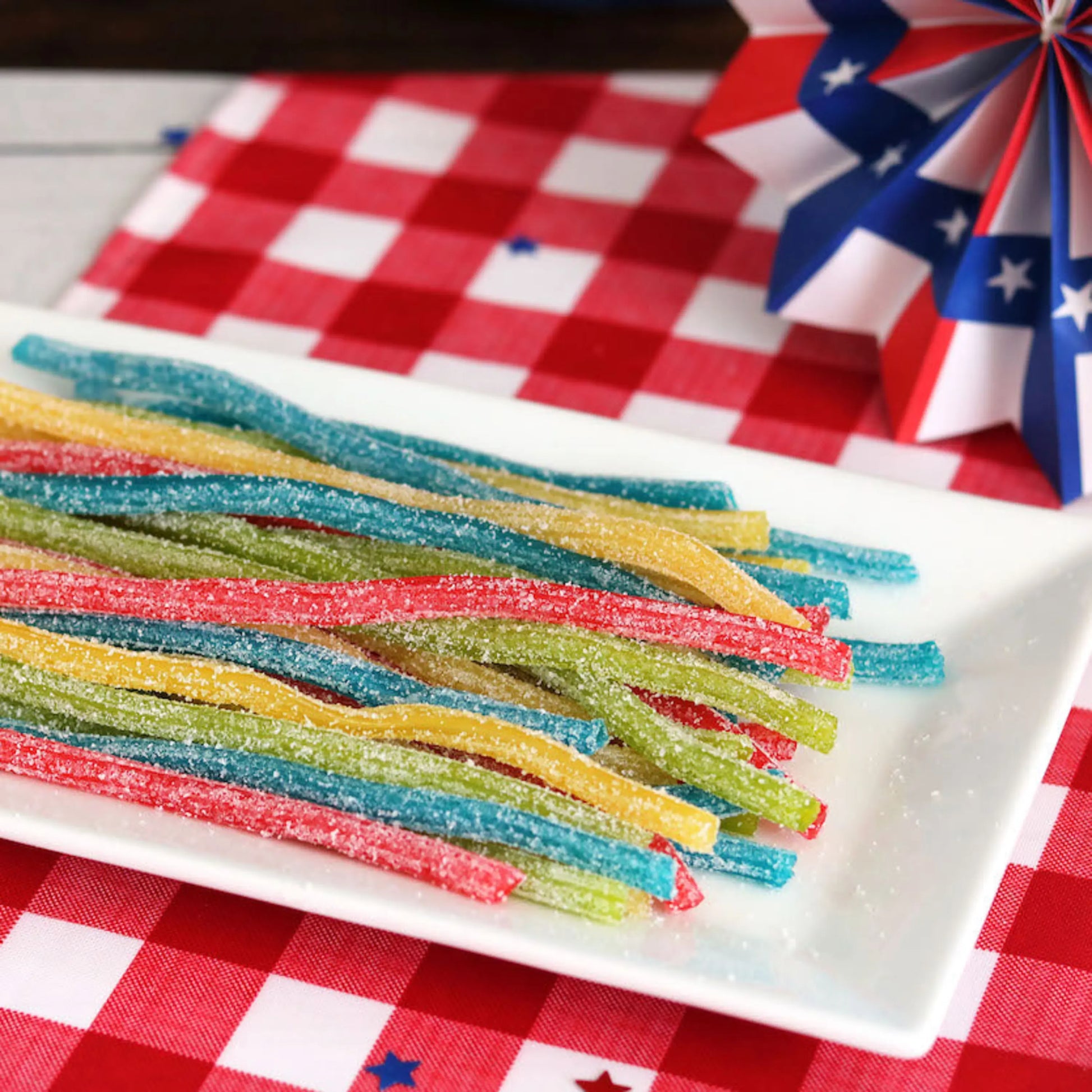 Sour Punch Rainbow Sour Candy Straws on a picnic table with patriotic decorations