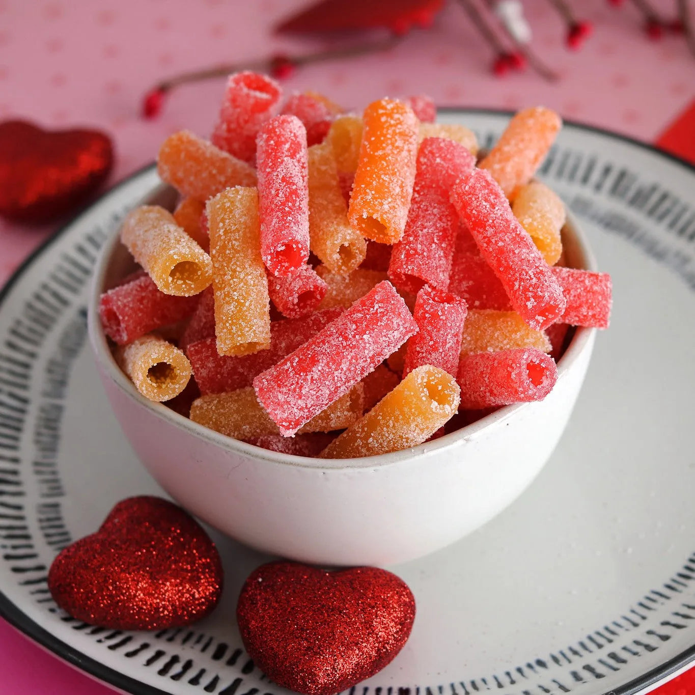 SOUR PUNCH Tropical Bites candy in a white bowl surrounded by red sparkle hearts