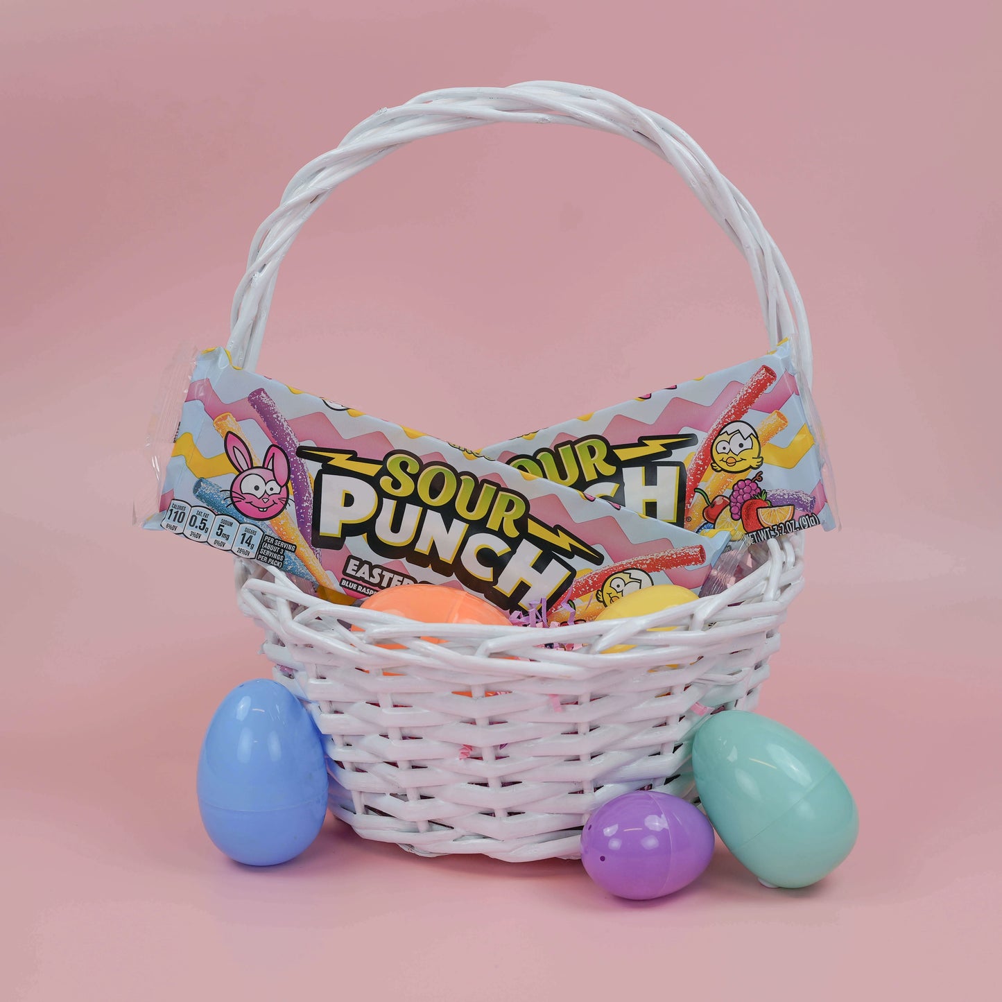 SOUR PUNCH Easter Candy Straws in a white Easter basket surrounded by plastic eggs