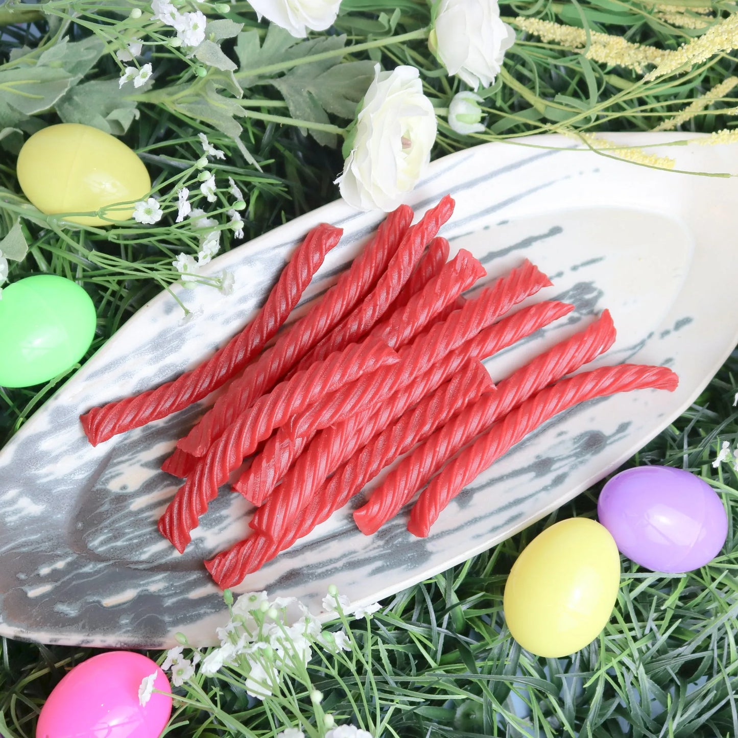 Red Vines Original Red Jumbo Licorice Twists on a platter surrounded by flowers and Easter eggs