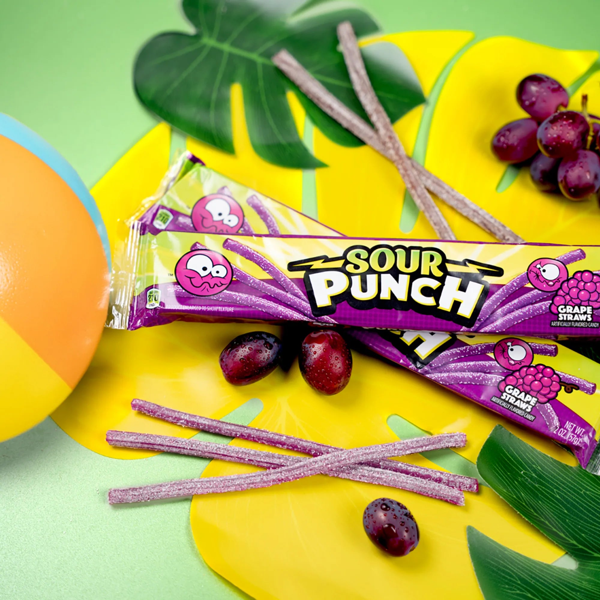 Purple candy straws with two Sour Punch Grape trays, grapes, and a beach ball