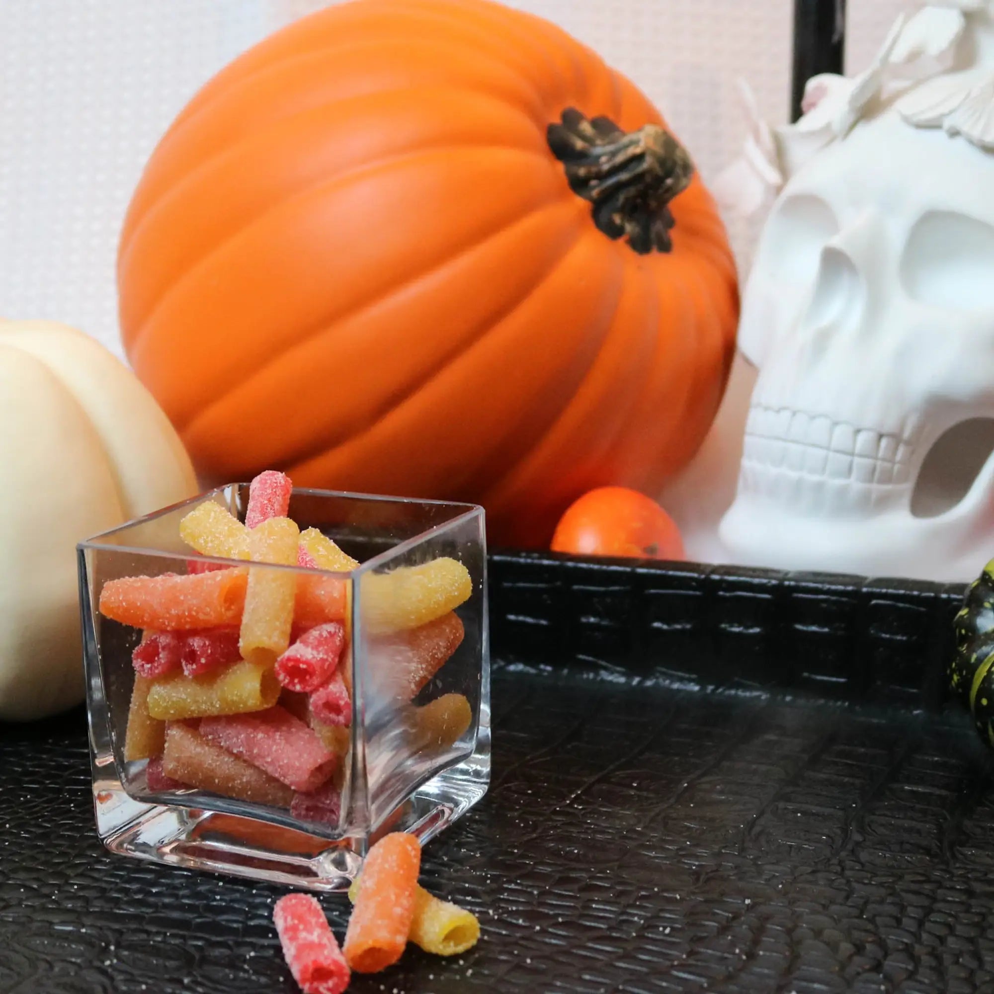 Sour Punch Tropical Bites Candy on a black tray with pumpkins and fake skulls