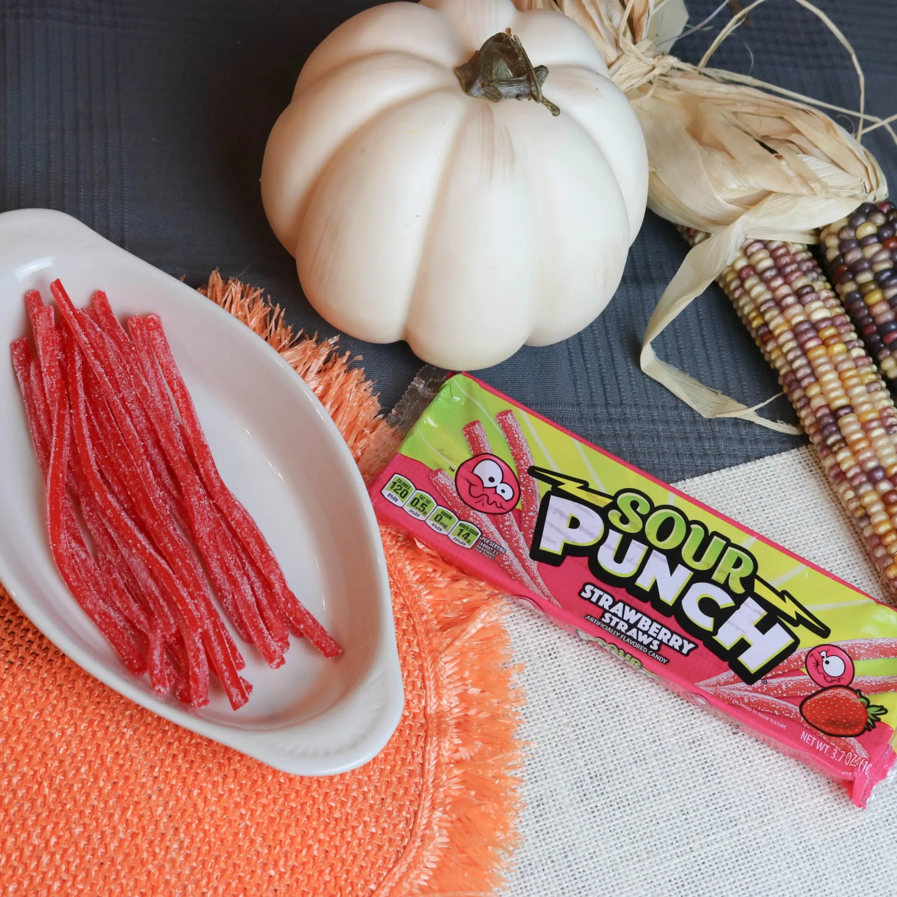 Sour Punch Strawberry Straws Candy in a white dish near a pumpkin and falltime props