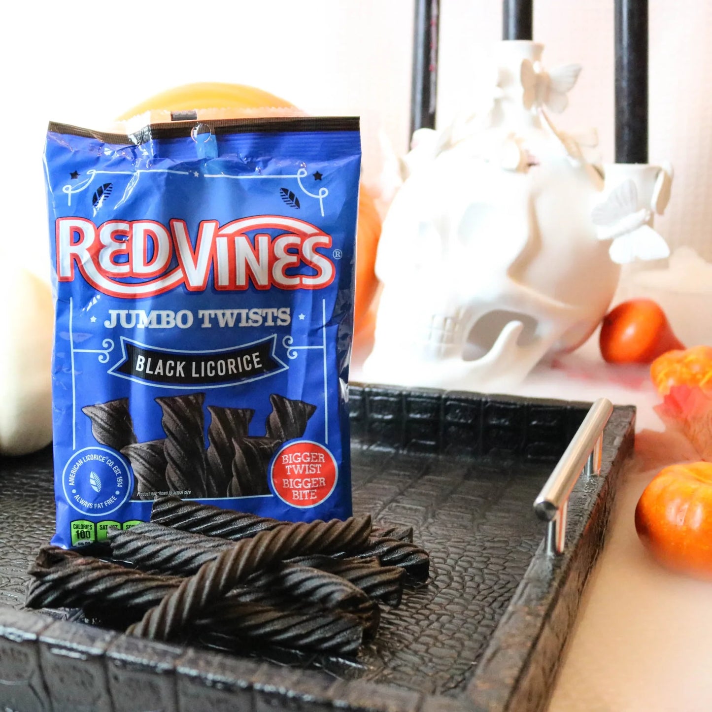 Red Vines Jumbo Black Licorice Candy on a black platter with pumpkins and fake skulls