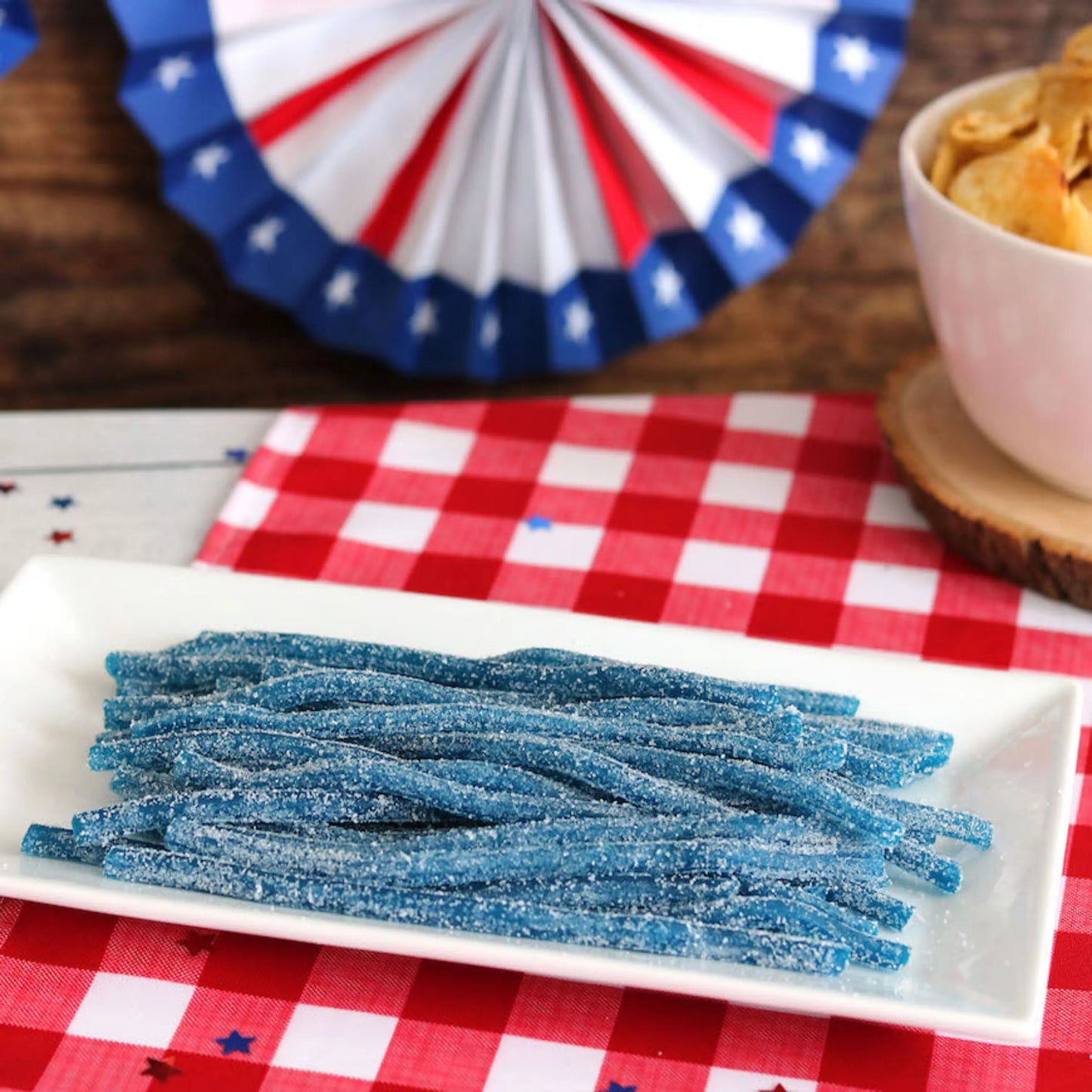 Sour Punch Blue Raspberry Straws Candy on a picnic table with patriotic decorations