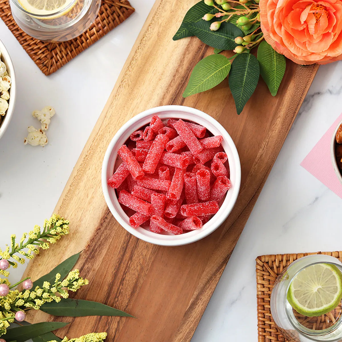 Sour Punch Strawberry Bites candy in a dish surrounded by spring flowers and other snacks