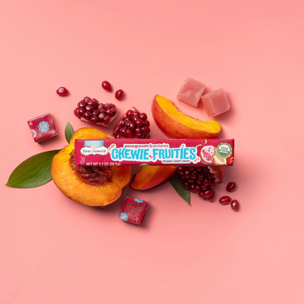Torie & Howard Chewie Fruities Pomegranate & Nectarine Candy stick pack on a bed of fresh fruit