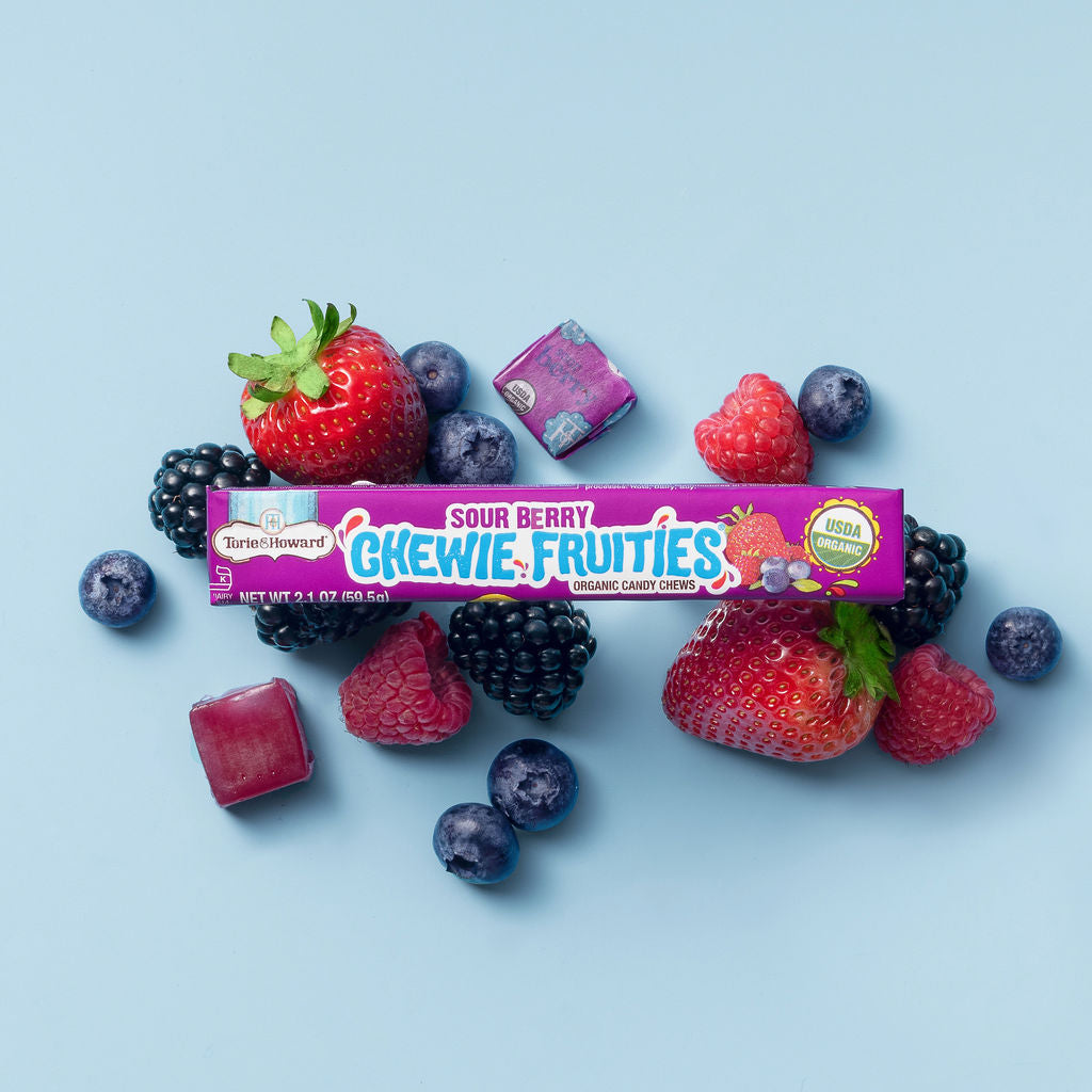Torie & Howard Chewie Fruities Sour Berry stick pack on a bed of fresh berries