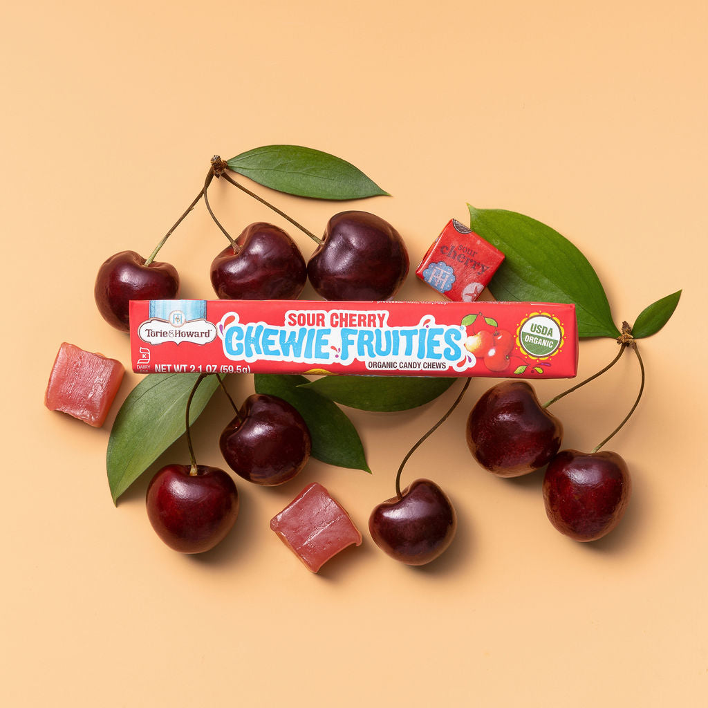 Torie & Howard Chewie Fruities Sour Cherry Candy stick pack on a bed of fresh cherries