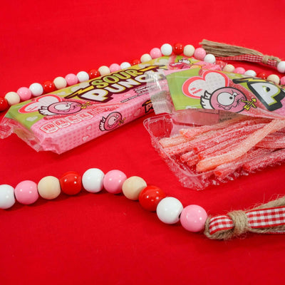 SOUR PUNCH Cupid Straws valentine candy trays on red tablecloth with valentine beads